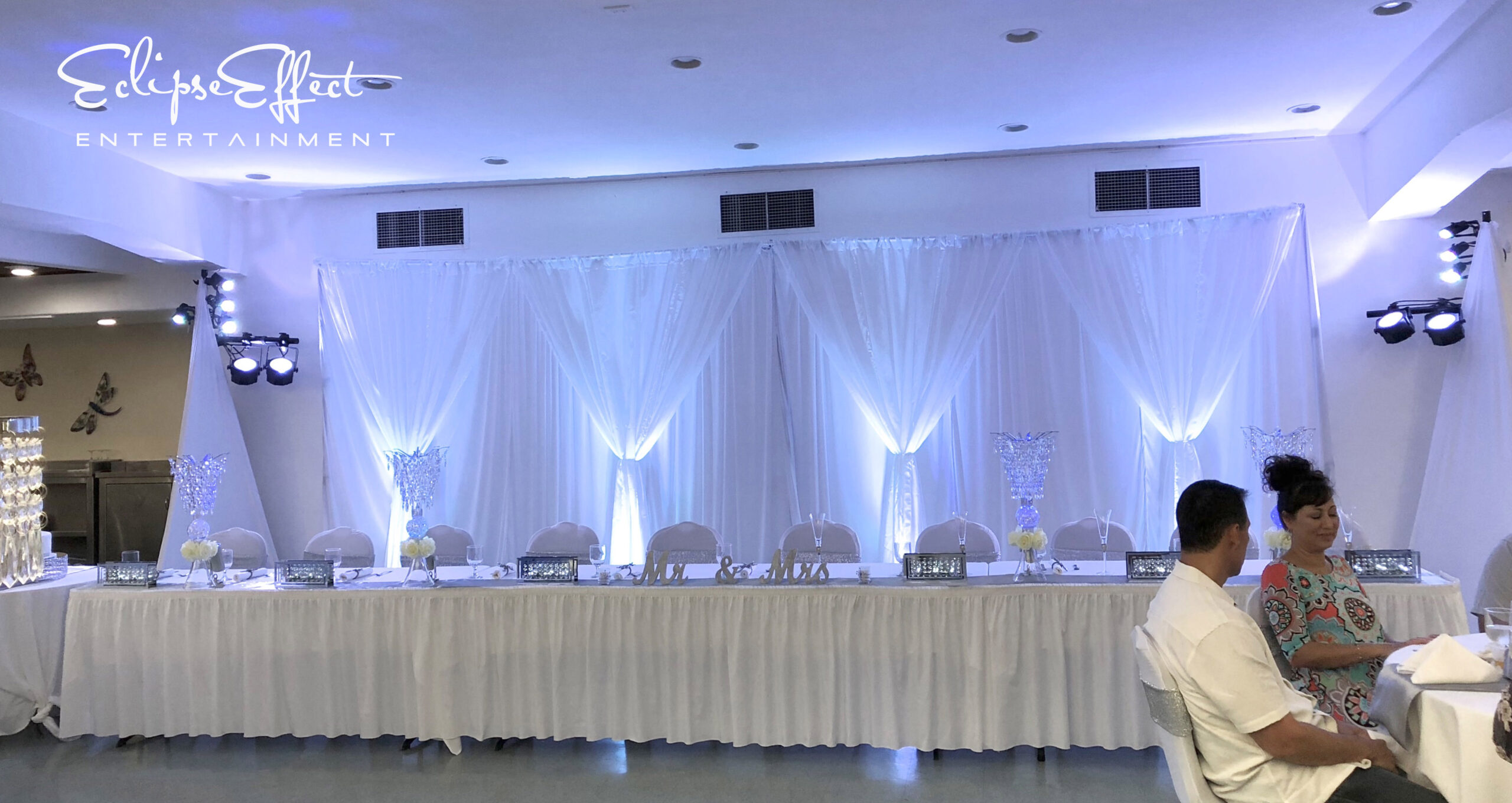 White uplighting on a head table backdrop.